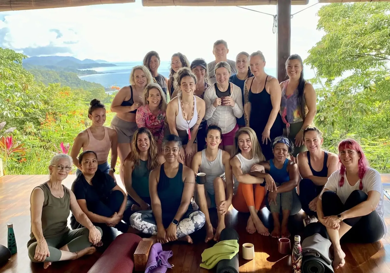 A retreat group sitting together on Anamaya's yoga deck with the Nicoya coast and Pacific Ocean behind them