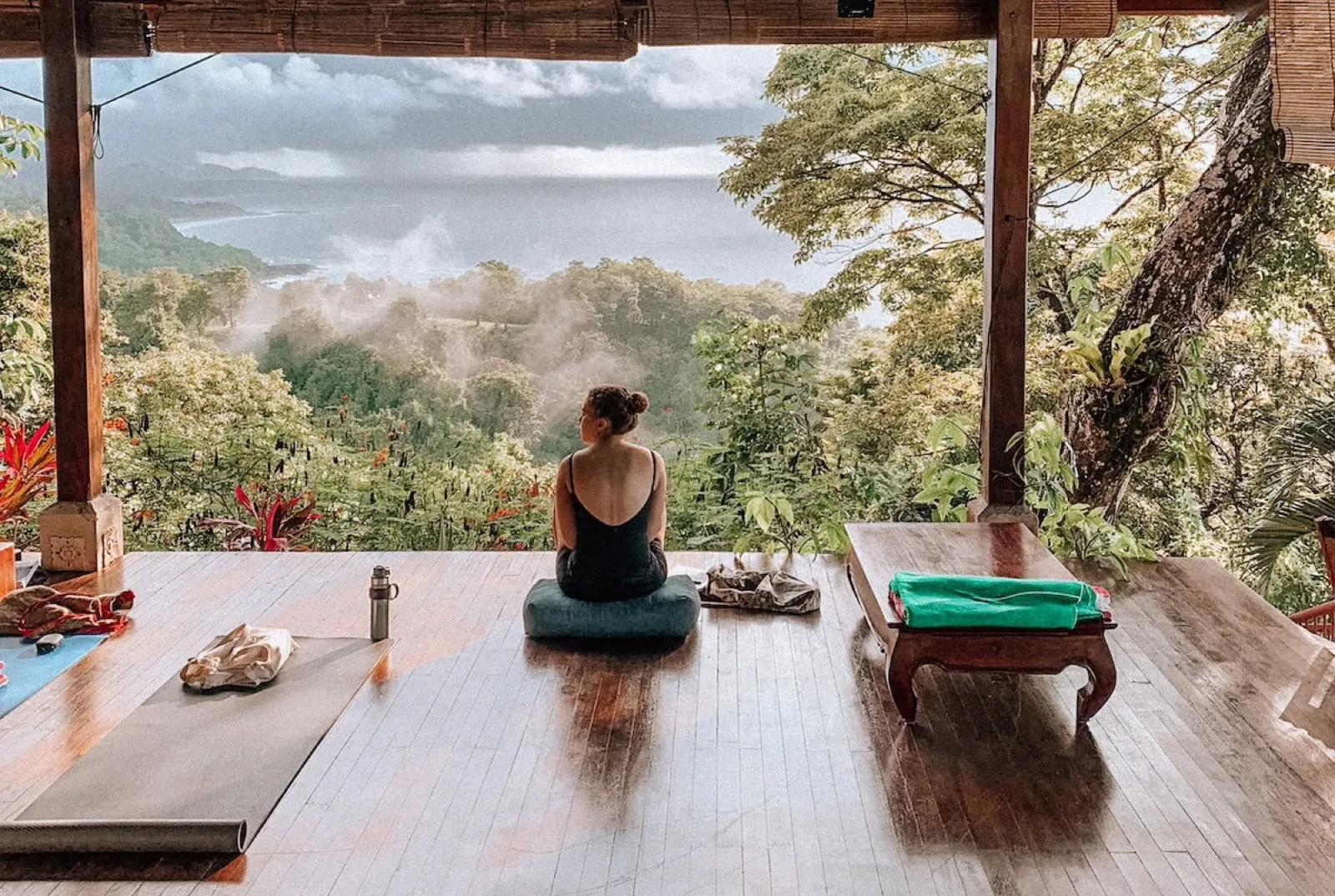 A guest sitting on Anamaya's open-air yoga deck, looking over misty rainforest to the Pacific Ocean at Montezuma